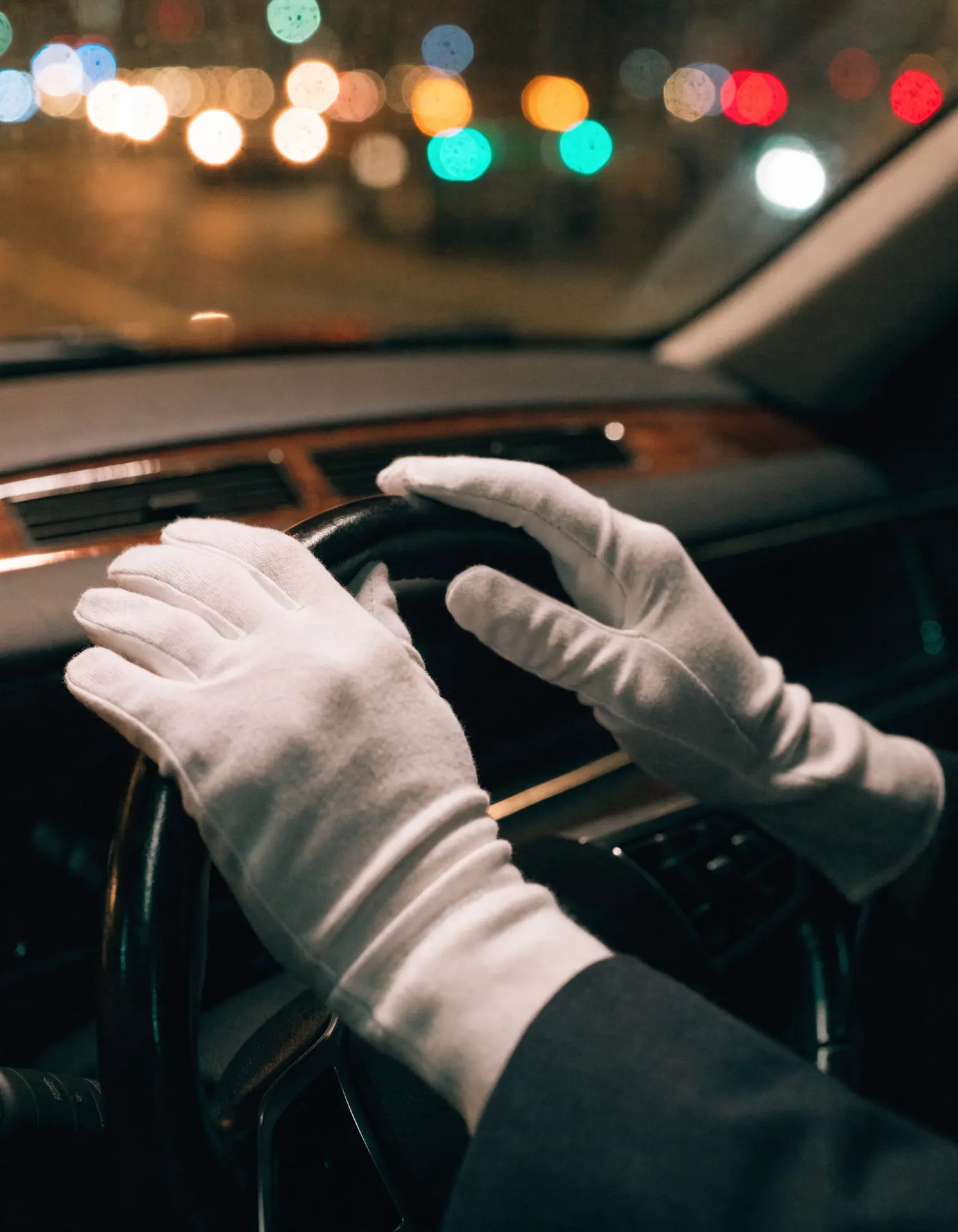 A chauffeur's gloved hands on the wheel, waiting planeside.